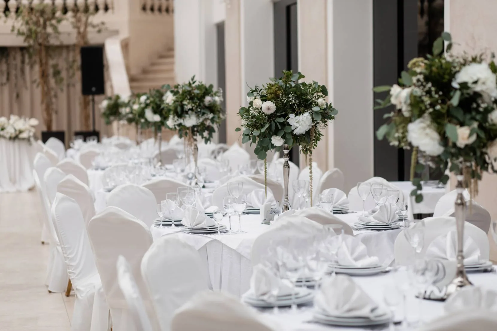 Elegant guest tables with tall white floral centerpieces at a formal event