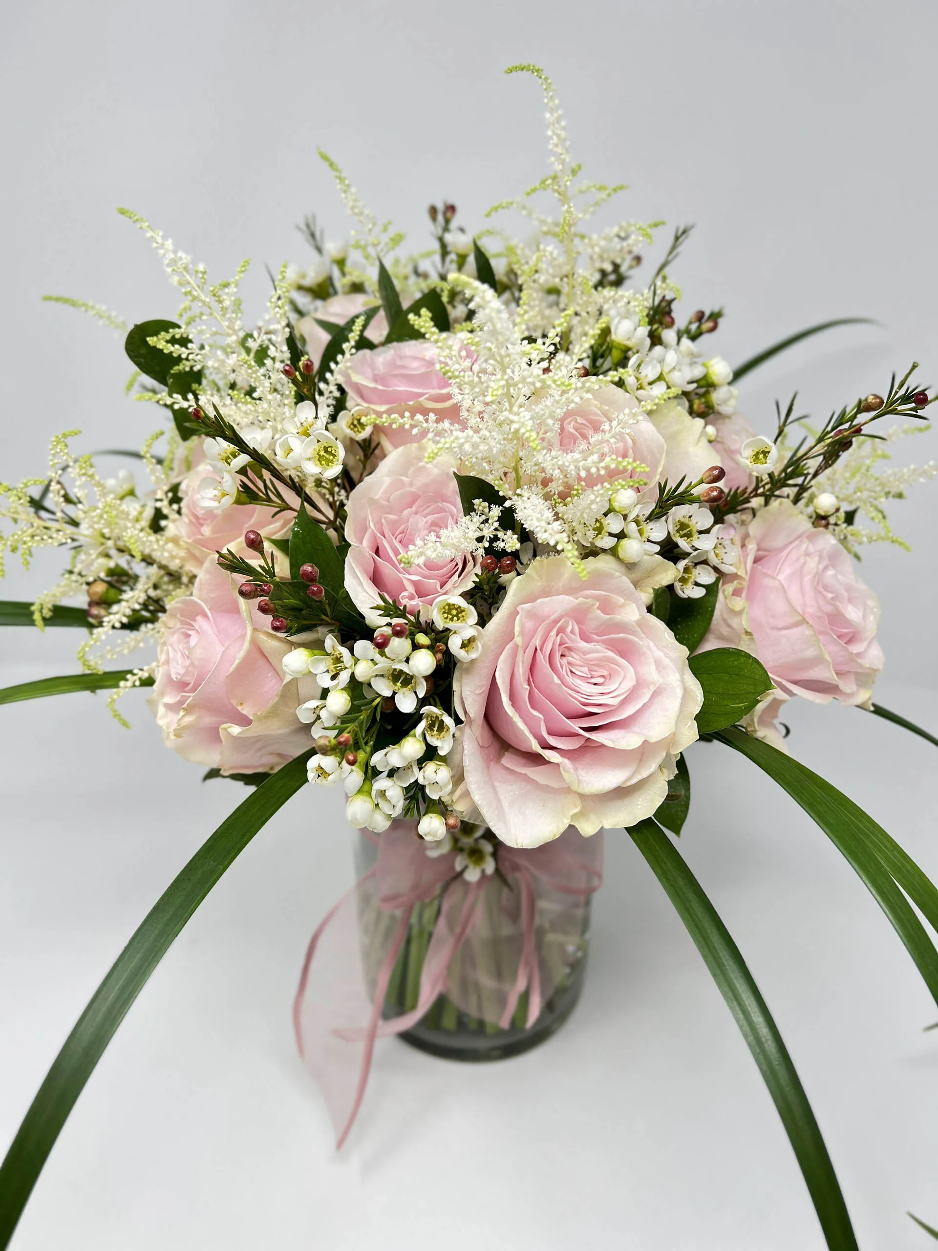 Pink rose vase arrangement with white astilbe and ribbon accents