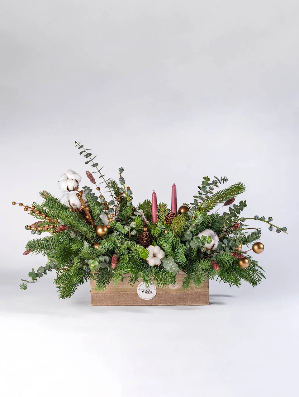 Christmas centerpiece Vancouver with evergreens, eucalyptus, cotton, pinecones, golden ornaments and red candles in a wooden box