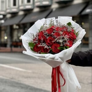 Crimson Romance Bouquet featuring red roses with delicate white filler flowers, wrapped in elegant white paper and tied with a red ribbon—available in customizable sizes of 18, 24, or 36 roses.
