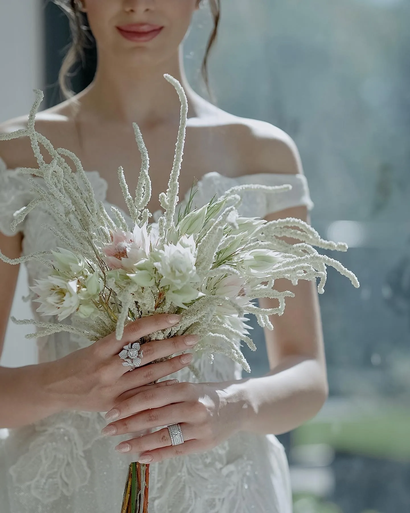 White and Blush Bridal Bouquet – Floba Flower Boutique Bride holding a delicate bouquet of white and blush flowers in an off-shoulder lace gown, styled by Floba Flower Boutique in Vancouver for a modern wedding.