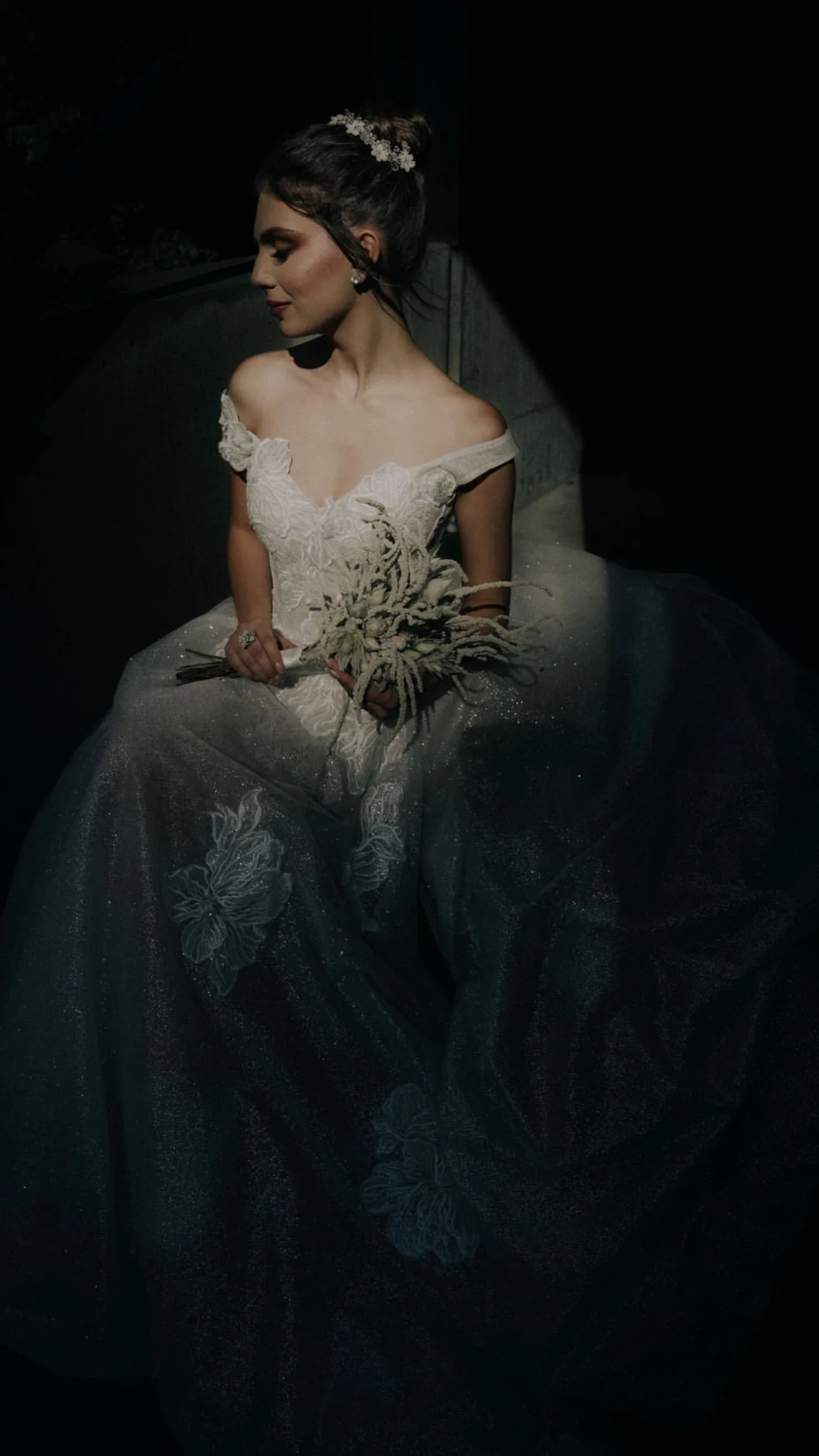 Dramatic Bridal Portrait with White Floral Bouquet – Floba Flower Boutique Bride in an elegant off-shoulder lace gown holding a minimalist white floral bouquet, captured in dramatic low light for a timeless wedding look by Floba Flower Boutique in Vancouver.