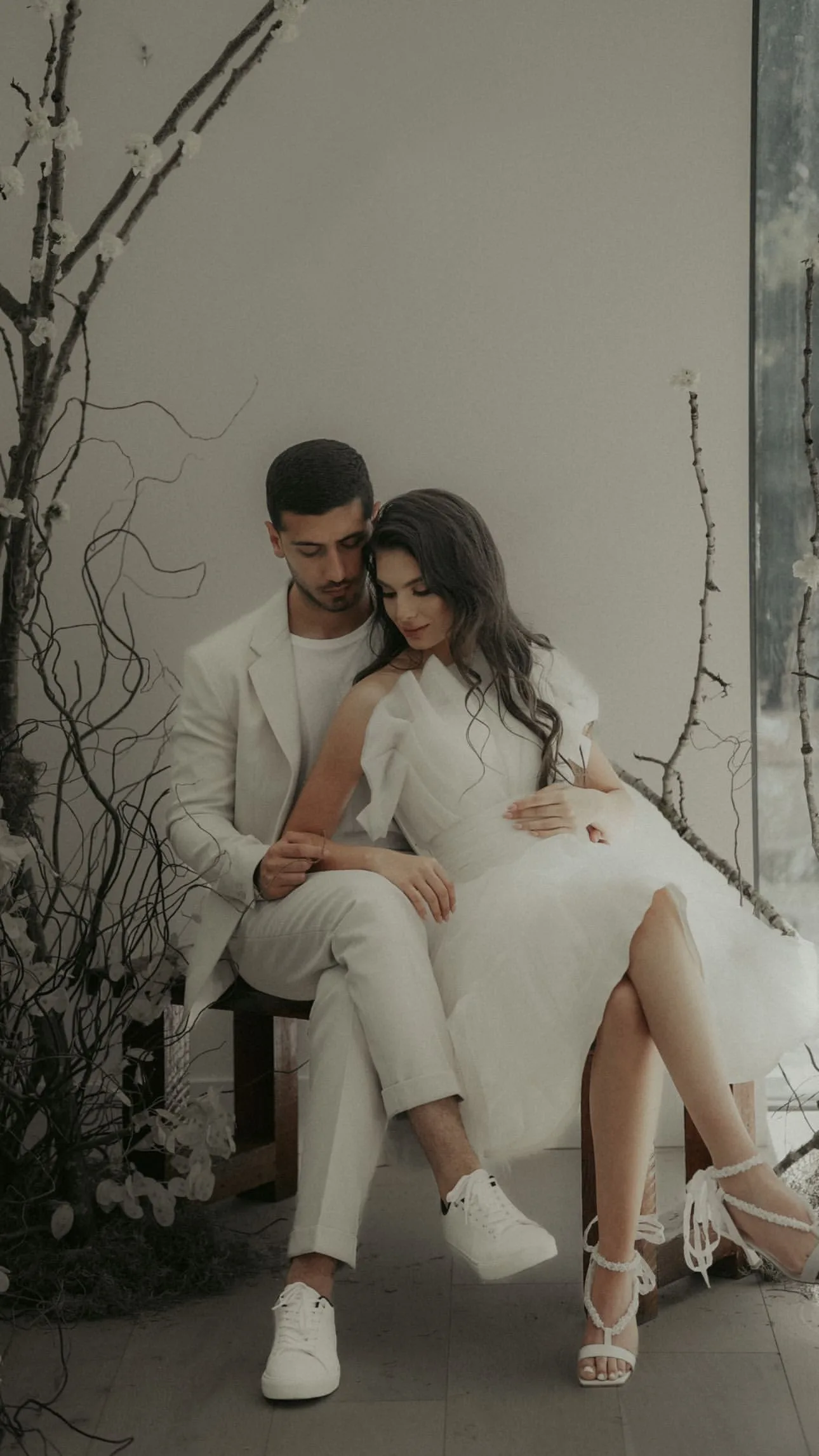 Romantic Minimalist Wedding Couple – Floba Flower Boutique Romantic couple in minimalist wedding attire seated in an elegant natural setting with branches and soft floral accents, styled by Floba Flower Boutique in Vancouver.