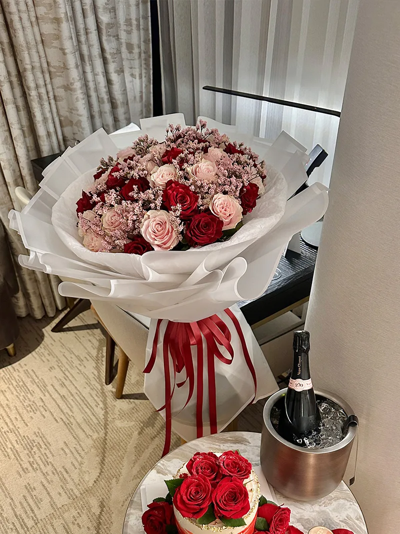 Blush Romance Bouquet featuring red and pink roses, accented with delicate baby's breath, elegantly wrapped in white paper with a red ribbon—perfect for anniversaries and romantic celebrations.