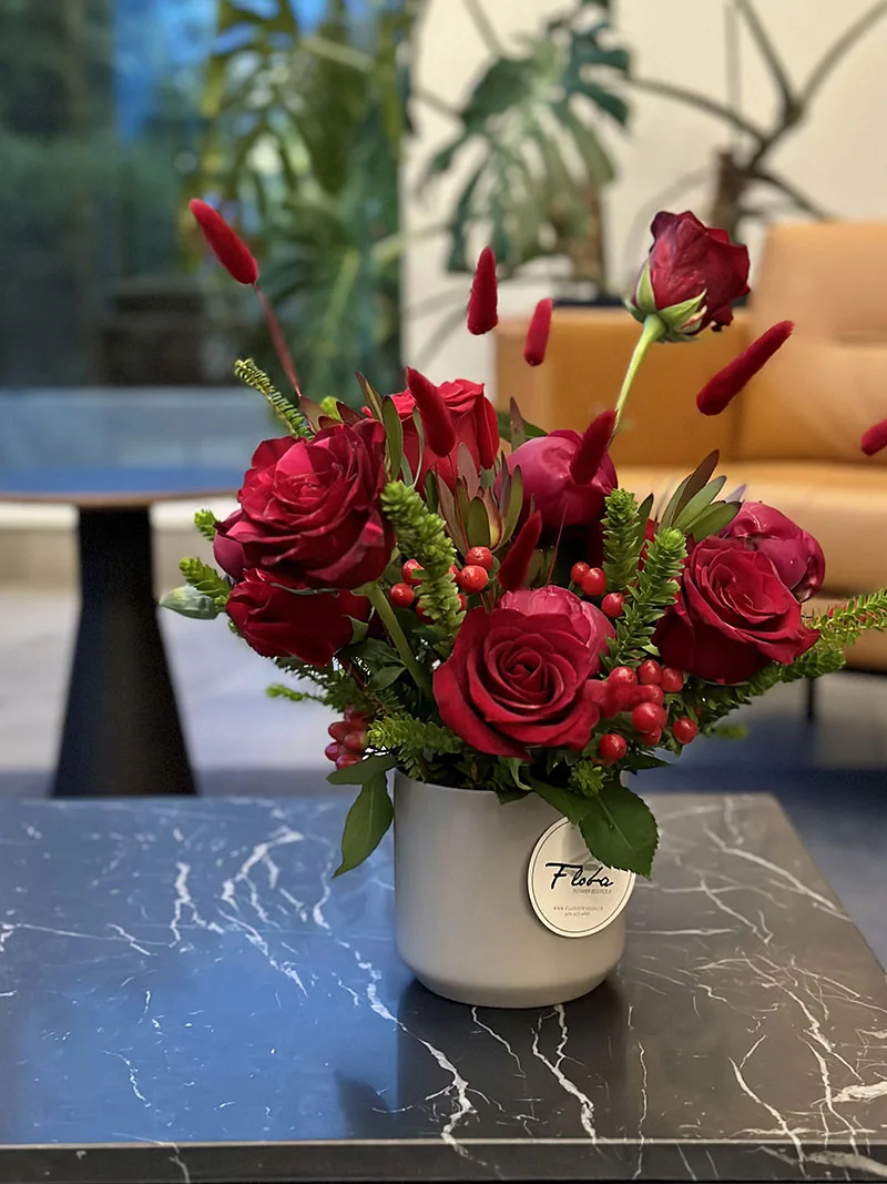 Elegant Ruby Radiance Arrangement with red roses and greenery in a white vase—perfect for romantic or celebratory occasions.