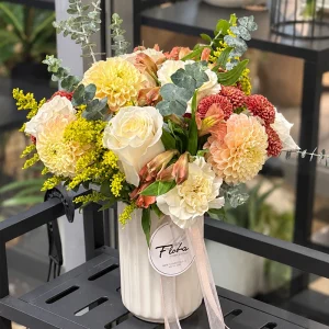 Peach & Honey flower arrangement with peach, cream and yellow blooms in a white ribbed vase